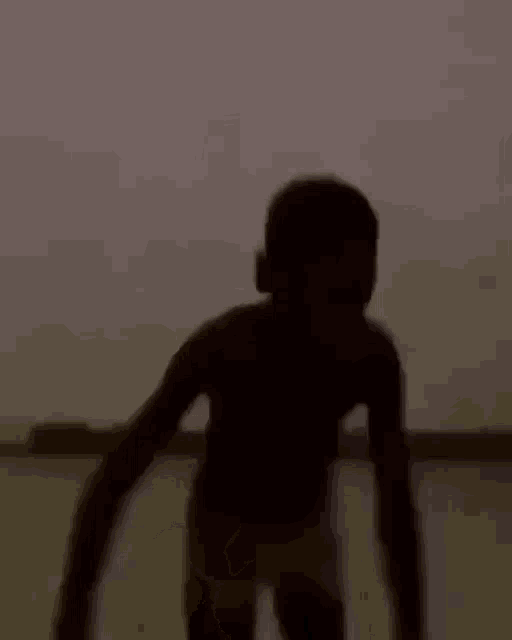 a silhouette of a person standing in the dark with their hands outstretched .