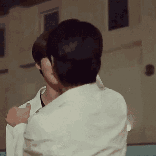 a man in a white shirt is hugging another man in a white shirt .