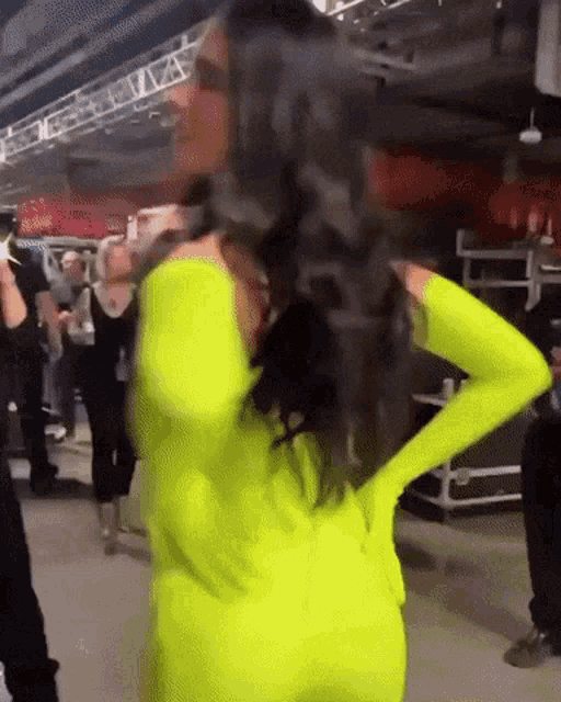 a woman in a neon yellow outfit is standing with her hands on her hips