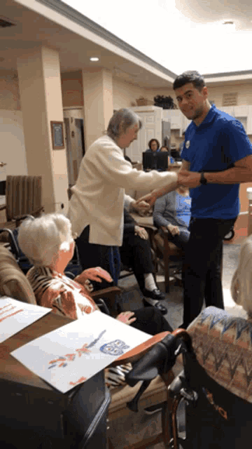 a man in a blue shirt is shaking hands with a woman in a white sweater