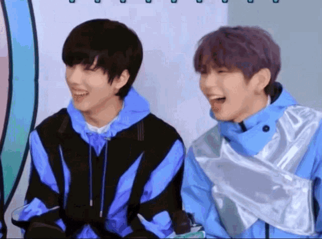 a couple of boys are laughing together and one of them has purple hair
