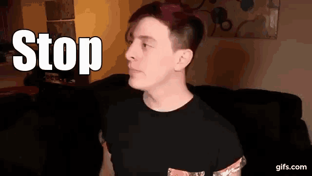 a man with red hair is sitting in front of a sign that says stop .