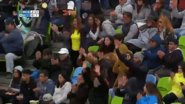 a crowd of people sitting in a stadium watching a game with a score of 2 to 7