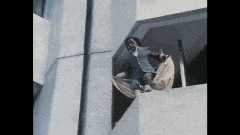 a man in a suit is standing on the side of a building holding a blanket .