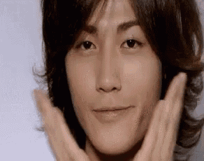 a close up of a man 's face with his hands on it .