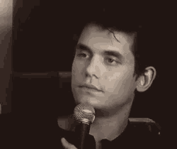 a black and white photo of a man holding a microphone