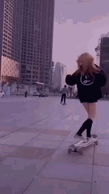 a girl is riding a skateboard with a smiley face on her sweatshirt