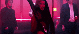 a woman is dancing in front of a group of men in suits in a red room .