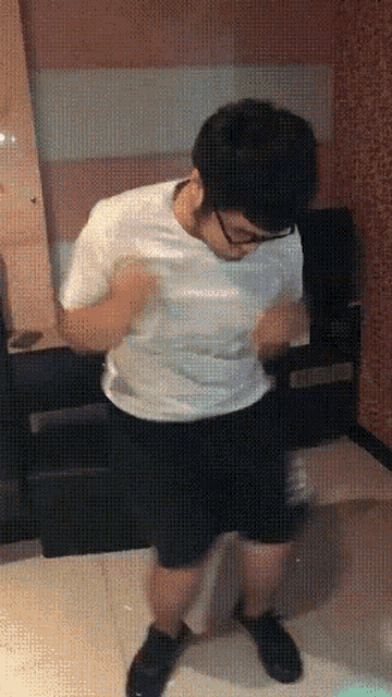 a man wearing glasses and a white shirt is dancing in a room