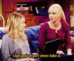 two women are sitting on a couch with a laptop and one says ugh god i can 't even fake it