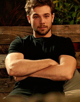 a man with his arms crossed is sitting on a wooden bench