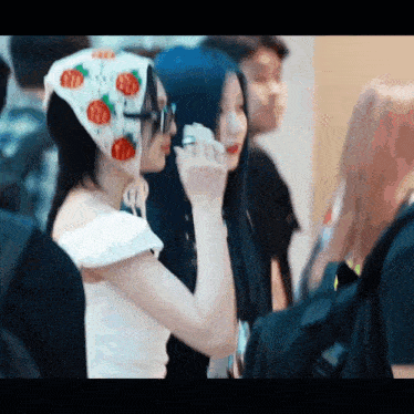 a woman wearing a scarf with strawberries on it talks on a cell phone