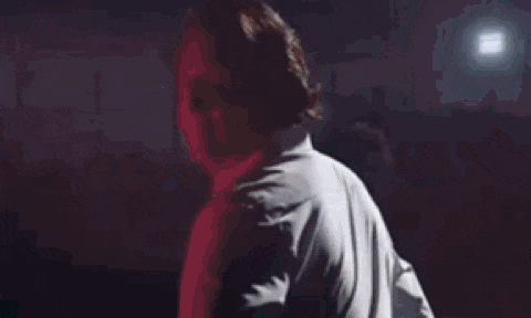 a man in a white shirt is making a funny face while standing in front of a crowd of people .