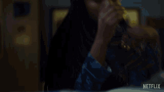a woman covering her face in a dark room with netflix written on the bottom
