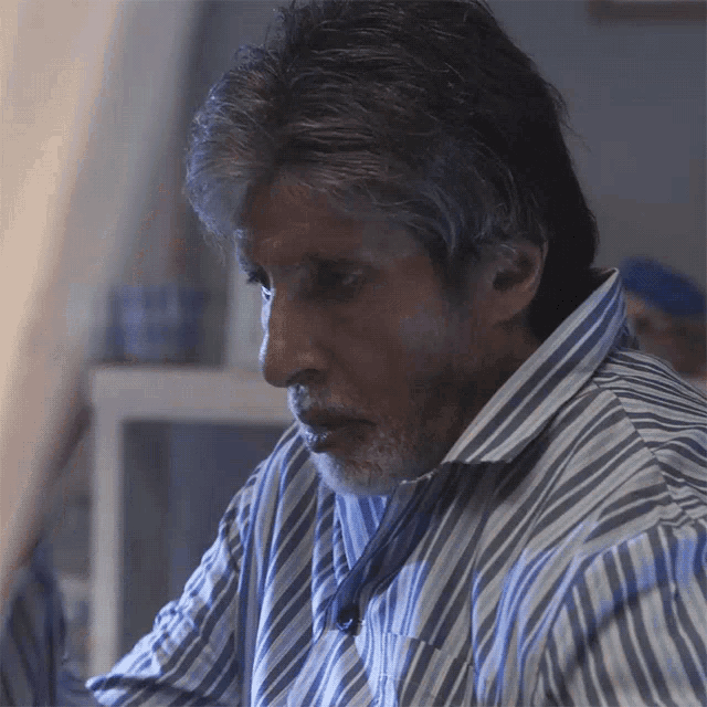 a man with gray hair and a beard wearing a striped shirt