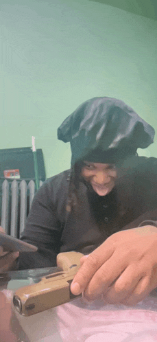 a person wearing a black hat is smiling and holding a gun