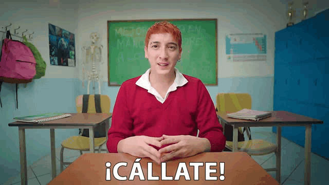 a boy in a red sweater sits at a desk in front of a chalkboard that says " mejor que un manolo ore