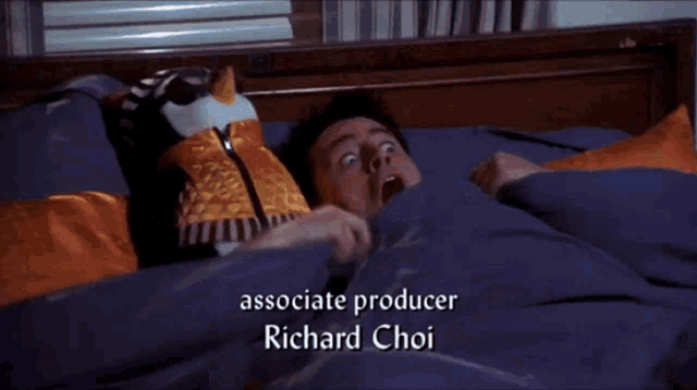 a man is laying in bed with his mouth open and the name richard choi is on the bottom of the screen