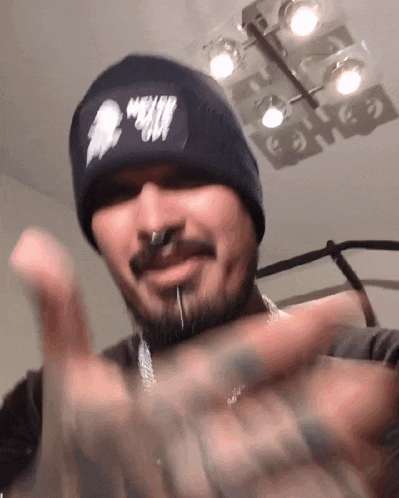 a man with a beard wearing a black beanie and a nose ring .