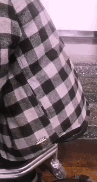 a person wearing a black and white plaid shirt that says oakley on it