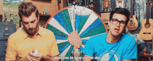 two men are sitting in front of a spinning wheel and one of them is saying " i want you to have a great day "