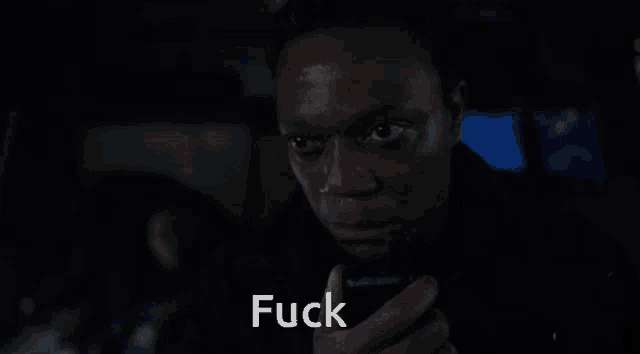 a close up of a man holding a cell phone with the word fuck written below him