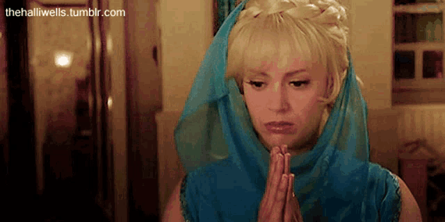 a woman with blonde hair and a blue scarf on her head is praying