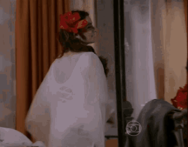 a woman with a flower in her hair is standing in front of a mirror