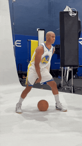 a man in a golden state warriors jersey is dribbling a ball
