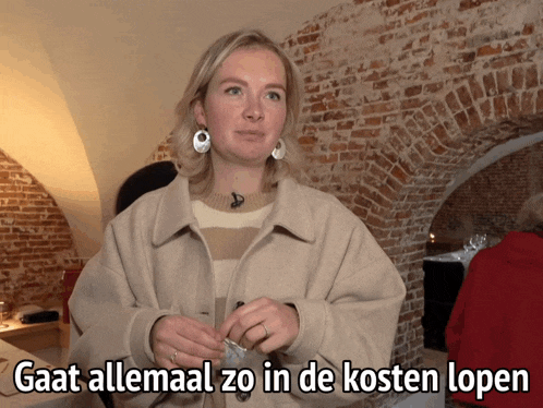 a woman is standing in front of a brick wall and says gaat allemaal zo in de kosten lopen