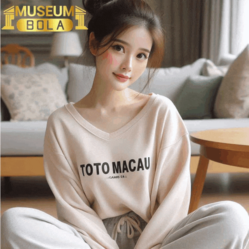 a woman wearing a toto macau sweater sits on the floor