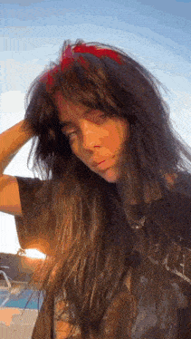 billie eilish is wearing a black t-shirt and a red headband .