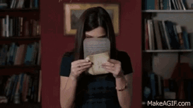 a woman is covering her face with a piece of paper .