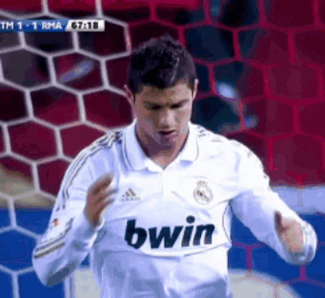 a soccer player wearing a white bwin jersey stands in front of a goal net