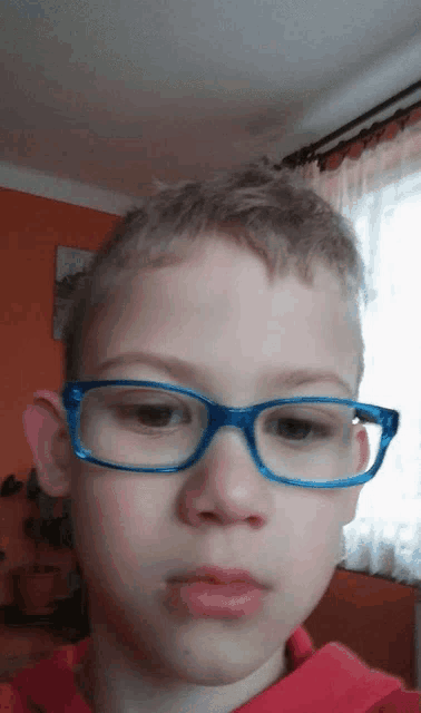 a young boy wearing glasses and a red shirt