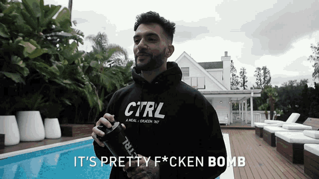 a man wearing a black sweatshirt that says ctrl stands in front of a pool