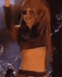 a woman in a crop top is dancing in a dark room .