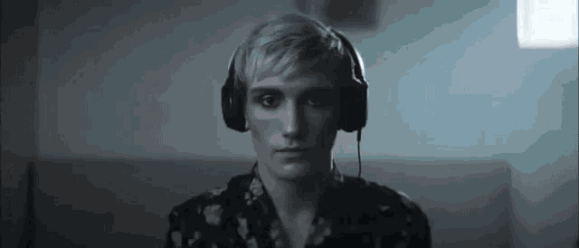 a man wearing headphones is sitting in a dark room looking at the camera .