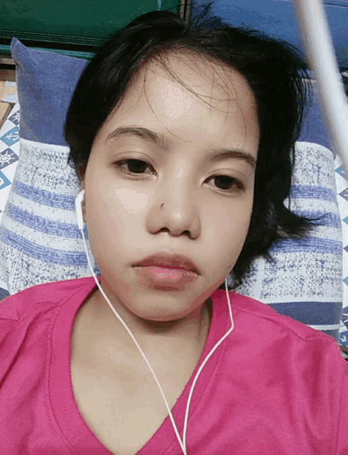 a woman wearing headphones is laying on a blue and white striped pillow
