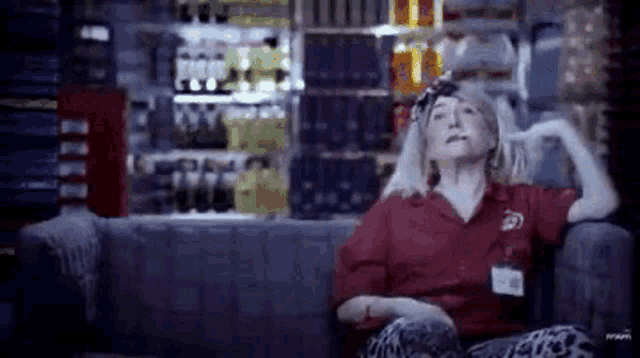 a woman is sitting on a couch in a store with her hands behind her head .