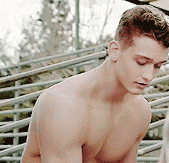 a shirtless man is standing next to a railing .