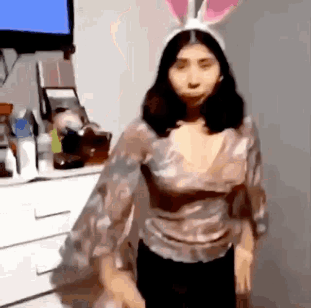 a woman wearing a bunny headband is standing in front of a television .