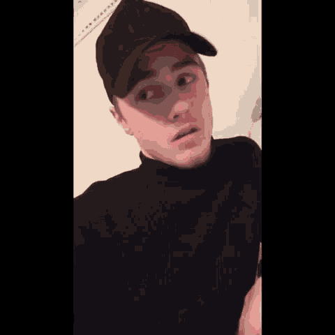 a young man wearing a ny hat and a black turtleneck sweater