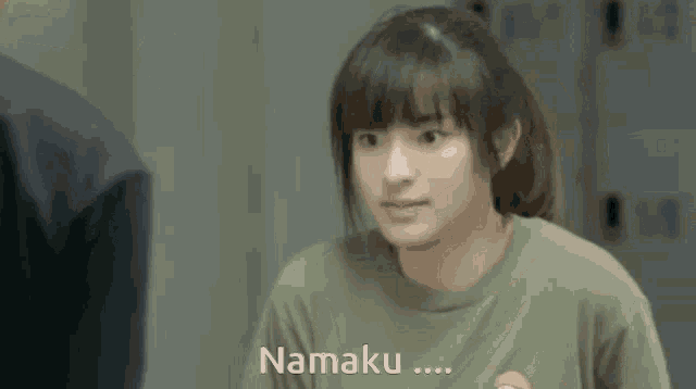 a girl in a green shirt is talking to someone and the word namaku is on the bottom