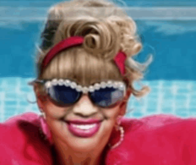a woman wearing sunglasses and a red headband is smiling