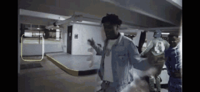 a man in a denim jacket is dancing in a parking garage with other people