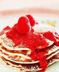 a stack of pancakes topped with raspberries and powdered sugar