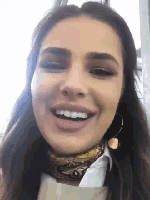 a woman wearing a scarf and hoop earrings is smiling and looking at the camera .