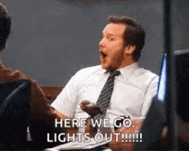 a man in a suit and tie is sitting at a table talking to another man and says `` here we go lights out !!! ''
