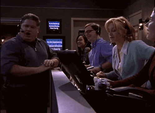 a group of people sitting in front of a monitor that says we are experiencing technical difficulties
